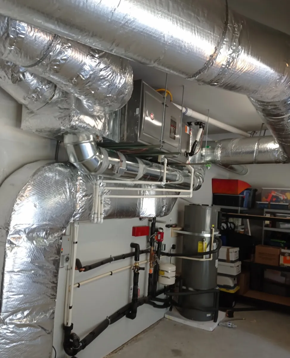 Mechanical room with ducts, air handler, tank, and piping
