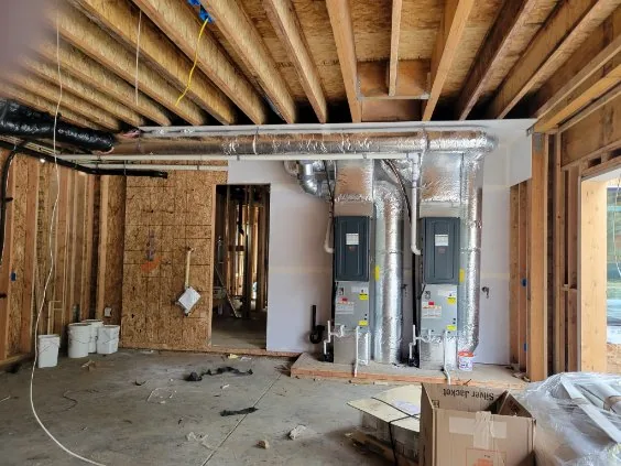 Dual furnace or air handler units on a raised platform with insulated duct and PVC drains